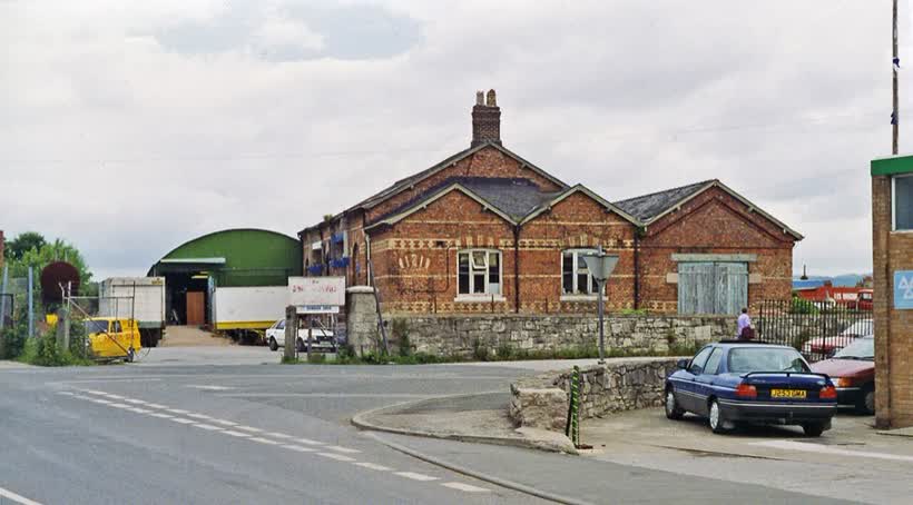 Denbigh station (remains), 1993. View northward from the A525, towards Mold and Chester: ex-LNWR line from Chester, which continued south to Ruthin and Corwen, also there was a branch from Rhyl. The station was closed to passengers 30/4/62, when the service Chester - Ruthin ceased (Ruthin - Corwen ceased 2/2/53), but goods continued to Denbigh from Rhyl until 1/1/68 although the passenger service from Rhyl had ceased from 19/9/55., close to the Aldi on Station Road, Denbigh